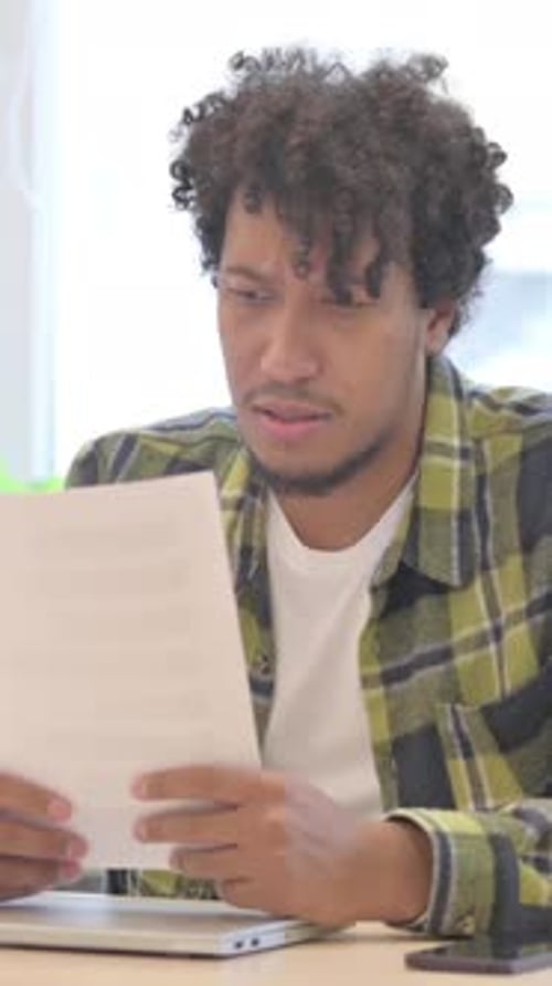 Worried Young Man Reads Documents at His Desk