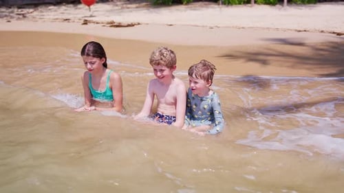 Kids Sitting In Shallow Water On A Beach
