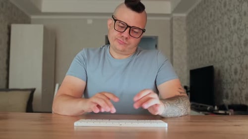 Man Typing on Keyboard at Wooden Table Indoors