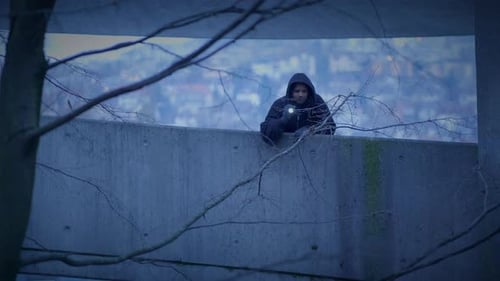 Teen with Flashlight Standing on Urban Bridge at Night