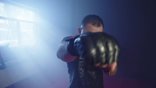 Fighter Practicing Punches with Boxing Gloves in Gym