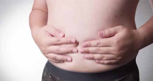 Close-up, male stomach, overweight. Young man with a naked fat belly shakes fat folds on his stomach