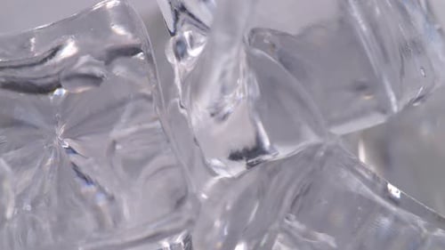 Close Up Of Drinking Water Being Poured Over Ice Cubes