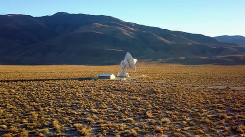 Aerial view towards a large Satellite dish at a desert - approaching, drone shot