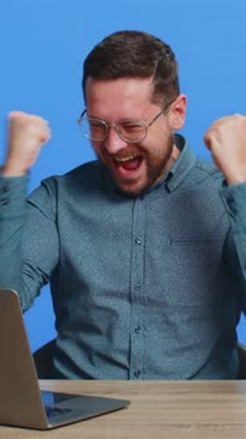 Enthusiastic Man Working on Laptop at Desk