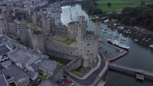 Ancient Caernarfon castle Welsh harbour town aerial view medieval waterfront landmark high up left d