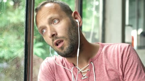 Man listening to music next to window