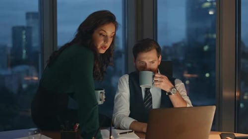 Smart coworkers discussing business project drinking coffee late evening in office