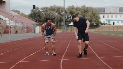 Two Young Adults Running and Exercising on Track