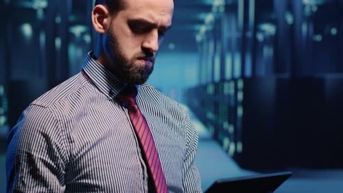 Data Center IT Engineer Standing Next to Server Cabinets