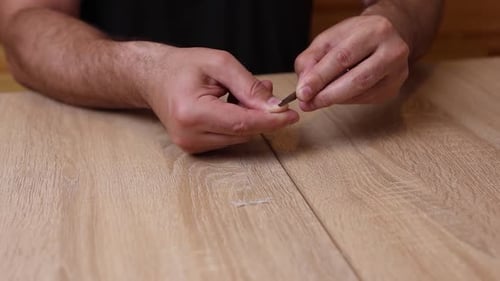 Adult Male Filing Finger Nail on Wooden Table
