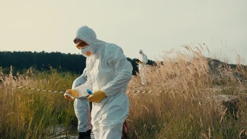 Researchers in Protective Suits Collecting Samples Near Water
