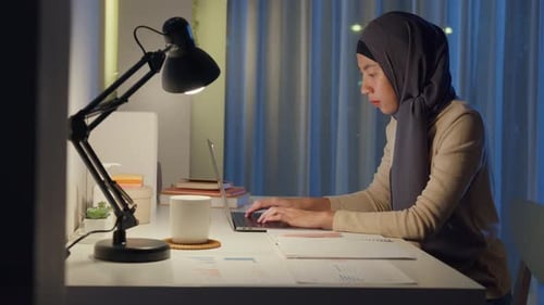 Woman Works on Laptop at Desk at Night