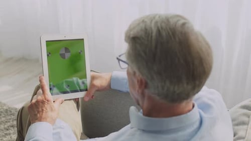 Senior Man Using Tablet with Green Screen at Home
