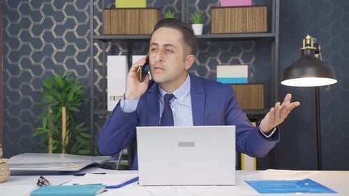 Man in Suit Talking on Cell Phone at Desk