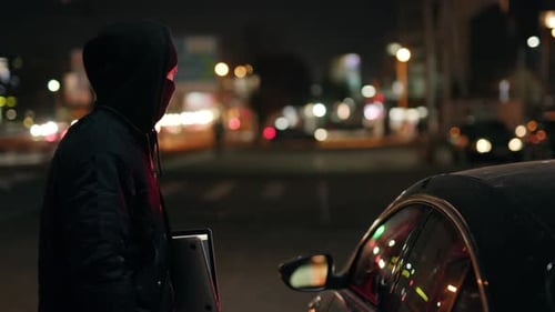 Man in Mask with Laptop Kneeling Next to Car