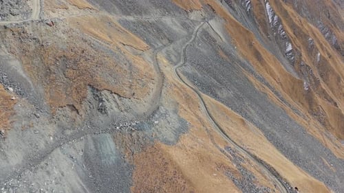 Luftaufnahme der kurvenreichen Bergstraße mit felsigem Gelände und lebendigen Farben