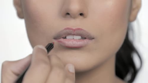 Woman applies red lip liner in close up
