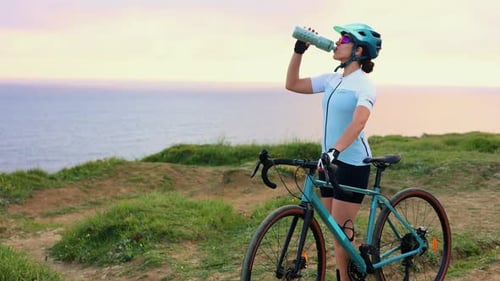 Latin cyclist woman drinking water from bottle on gravel bike