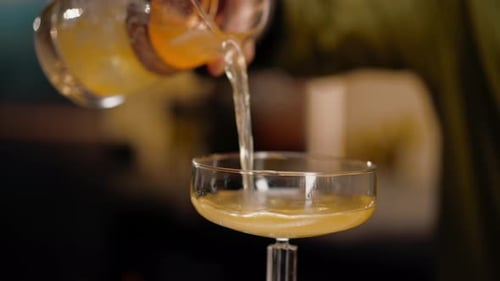 Erfahrener Barkeeper gießt in der Bar frischen, leckeren alkoholischen Cocktail aus dem Messbecher in ein Glas