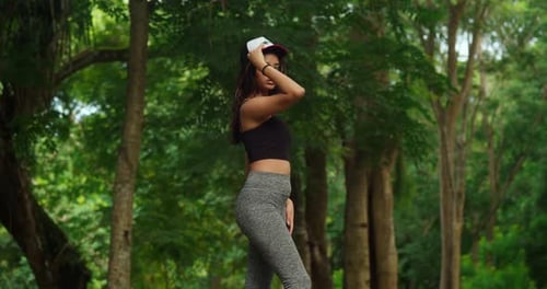A young girl, clad in sports wear, embraces the active lifestyle in a tropical park.