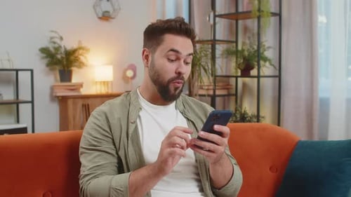 Man Sitting on Couch Using a Mobile Phone