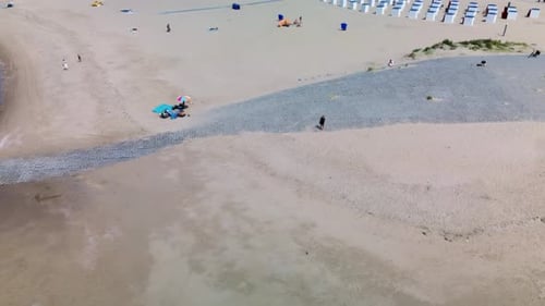 A beautiful aerial view of a sandy beach with rows of beach huts, people relaxing by the shore