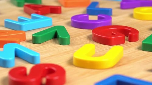 Multicolored letters rotate on a wooden background. The concept of learning, school or college