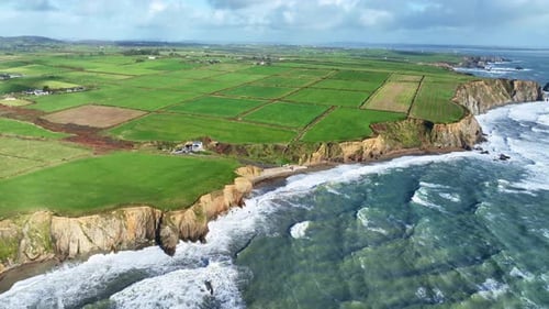 Breathtaking Aerial View of Green Coastal Farmland and Rugged Cliffs