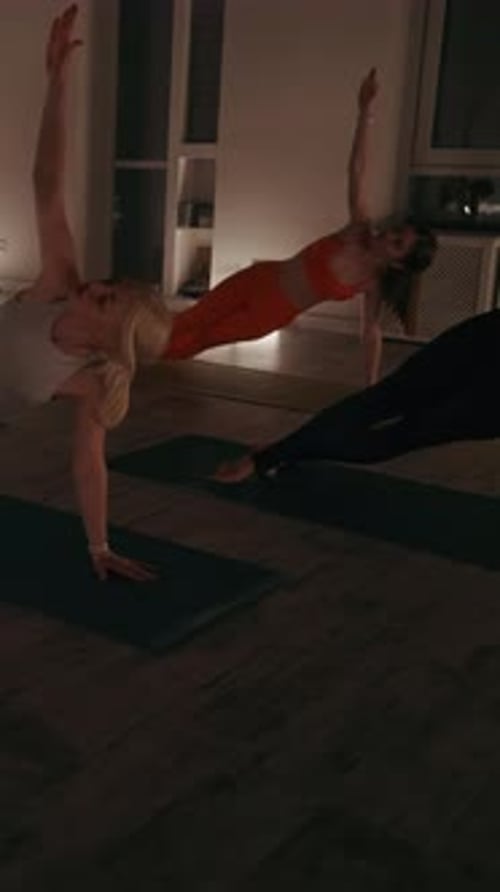 Vertical screen: Women Performing Side Plank Pose in Yoga Class