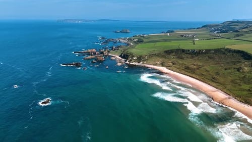 Green rocky shore of Ireland with rare houses scattered by the valley.