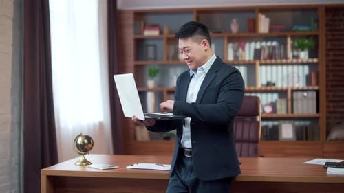 Happy young Asian employee uses a smartphone in the office. Satisfied business man worker texting