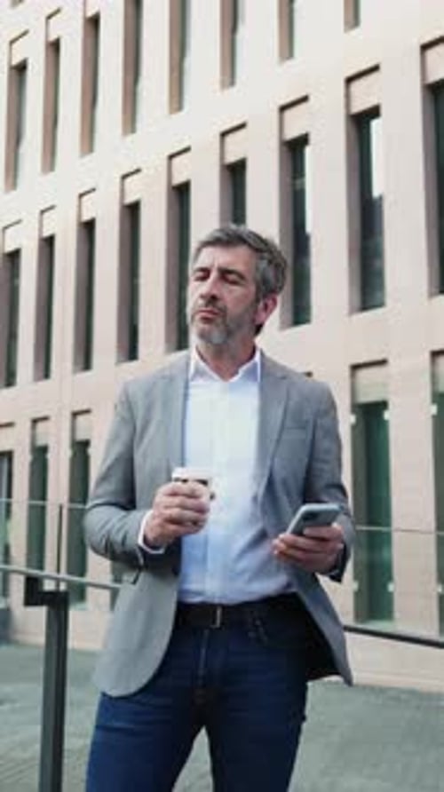 Man With Coffee Using Phone Outside Modern Building