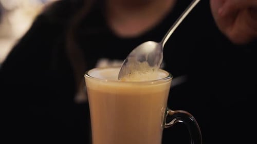 Stirring Latte with Spoon in Glass