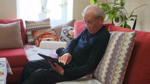 Senior Man Relaxing on Couch Using Tablet