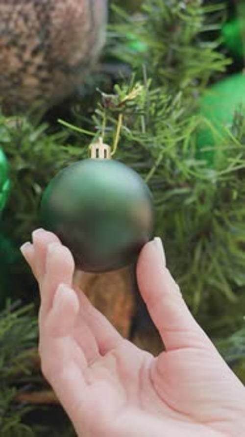 CloseUp of Hand Holding Green Decorative Christmas Ball From Tree