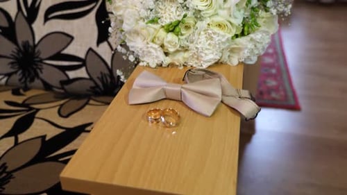 33. Two gold wedding rings, a wedding bouquet and a bow tie.