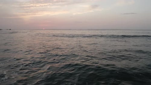 Sonnenuntergang über ruhigem Meer, sanftes Licht auf der Wasseroberfläche und dunstiger Himmel, ruhige Meereslandschaft
