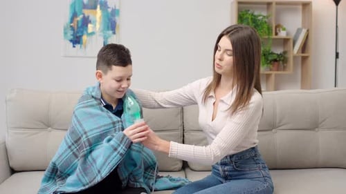 Woman Helping Boy with Nebulizer Treatment at Home