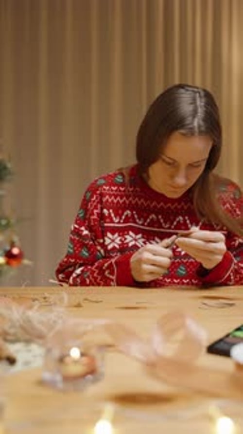 Woman Crafts Holiday Decorations at Table Indoors
