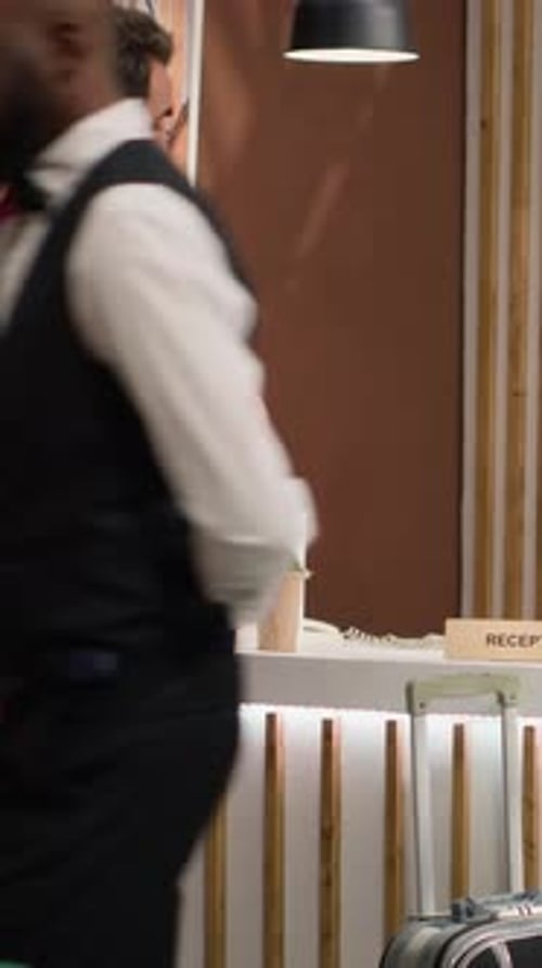 Hotel Receptionist Assists Guest in a Maroon Suit