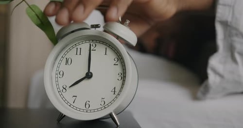 Nahaufnahme in Zeitlupe eines Mannes, der den Wecker ausschaltet, in einem bequemen Bett schläft und die Ruhe genießt