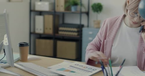 Business Lady Discussing Work on Mobile Phone Checking Papers and Using Computer Indoors in Office
