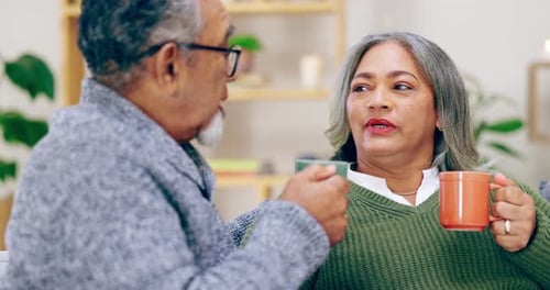 Adult Couple Talking and Holding Mugs Indoors