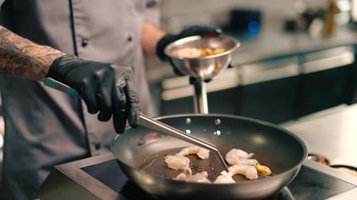 Professional kitchen in the restaurant of the hotel the chef lays out seafood with tongs on a pan