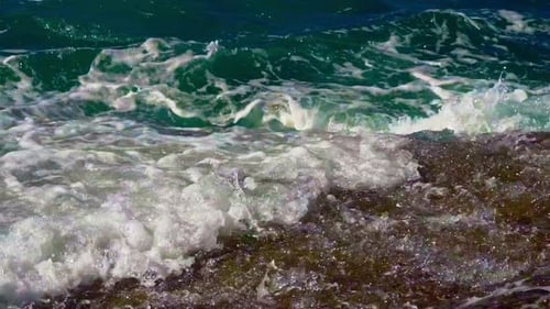 Le mouvement de la mer sent de puissantes vagues éclabousser la pierre. L'eau côtière se déplace rapidement, les vagues semblent sauvages