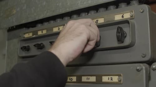 Hand Flips Switches on Industrial Control Panel