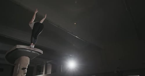From Below Back View of Young Female Gymnast Jumping From Vault and Performing Backflip During