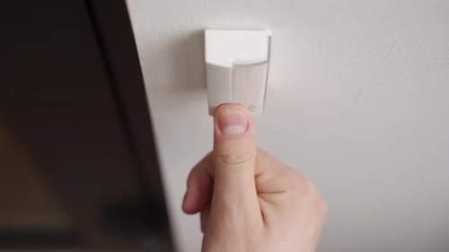 Finger Pressing Light Switch on Wall