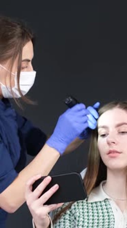 A Trichologist Examines the Patient's Hair with a Trichoscope in the Clinic Vertical Video